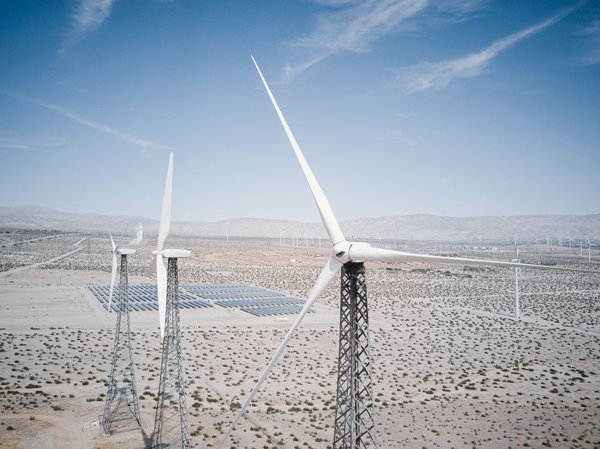 Wind turbines and solar panels generating renewable energy in a desert landscape.