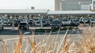 A large parking lot with solar panels covering parked cars at a commercial building.