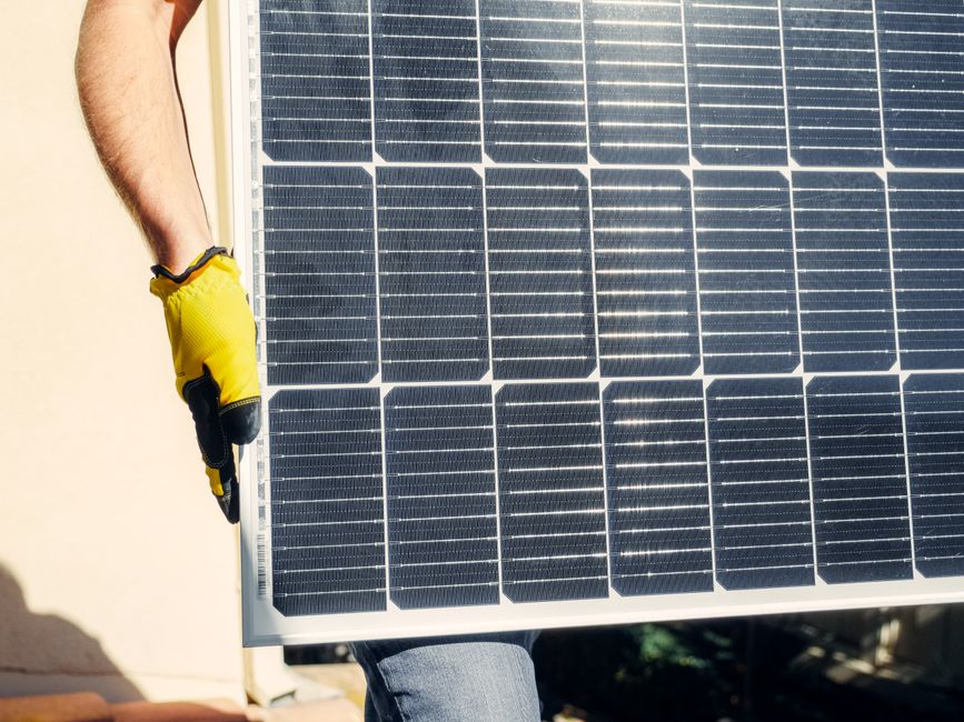 Close-up of a person installing a solar panel outdoors under bright sunlight.