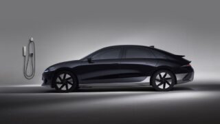 Side view of a black electric car in a studio, showcasing sleek design and charging station.