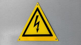 Close-up of a yellow high voltage warning sign mounted on a wall.