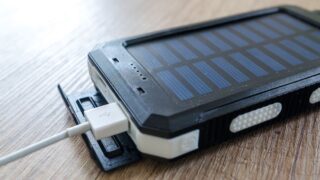 A close-up of a solar charger with a USB connection on a wooden surface, showcasing modern technology.