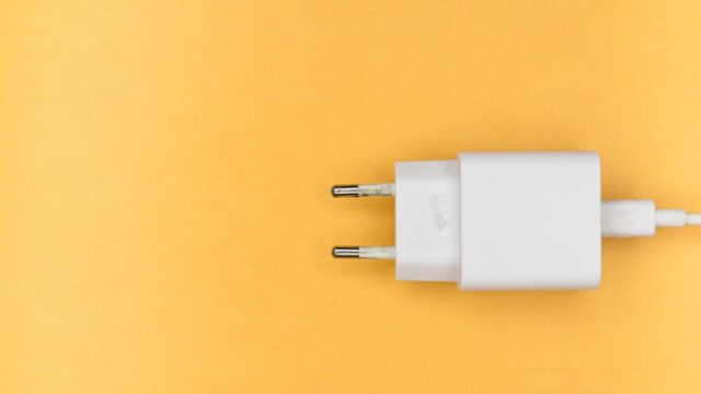White charger plug on a clean yellow background, perfect for tech themes.