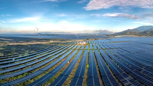 Expansive solar farm and wind turbines harnessing renewable energy at sunrise, showcasing sustainable technology.