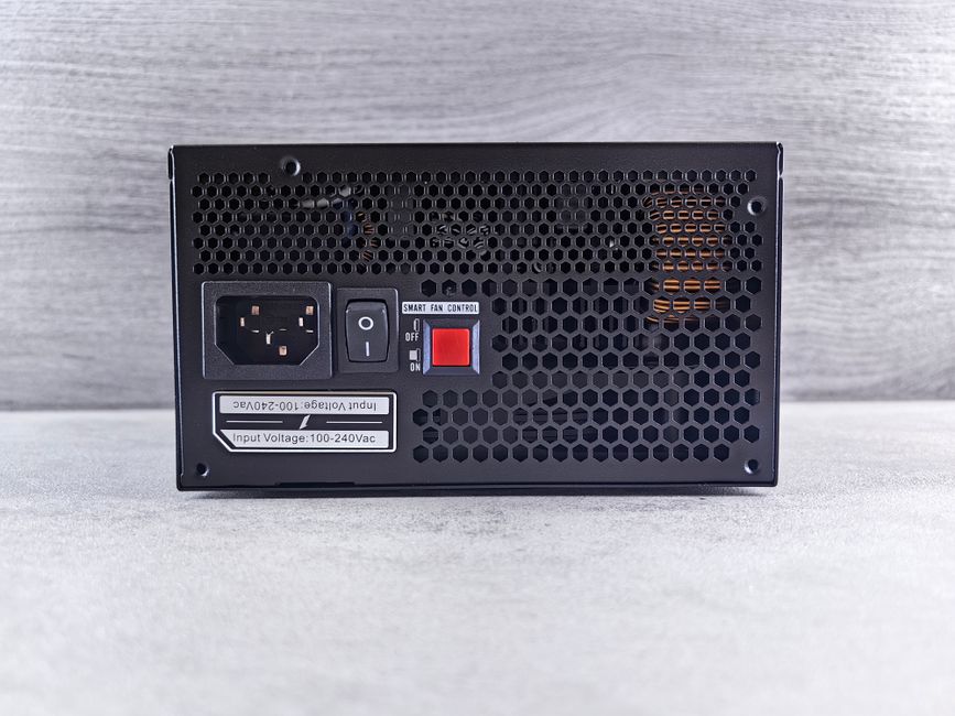 Detailed view of a computer power supply unit back panel with power socket, switch, and ventilation grill.