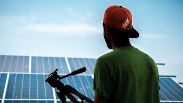 A person in a cap films a solar panel installation, promoting sustainable energy solutions.