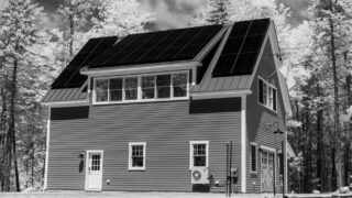 Contemporary house with solar panels in a forest setting, symbolizing sustainable living.