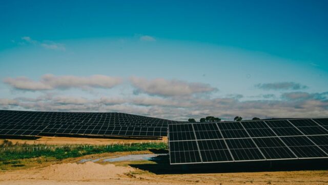 A vast solar farm in a desert setting under clear blue skies, showcasing renewable energy.