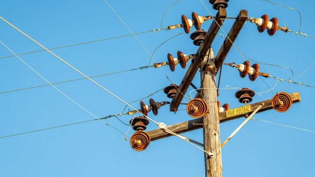 High voltage power line and insulators captured against a clear blue sky.