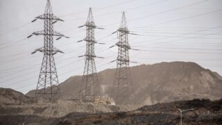 High voltage power lines and steel towers stretch across an industrial landscape in Zaporizhzhia, Ukraine.