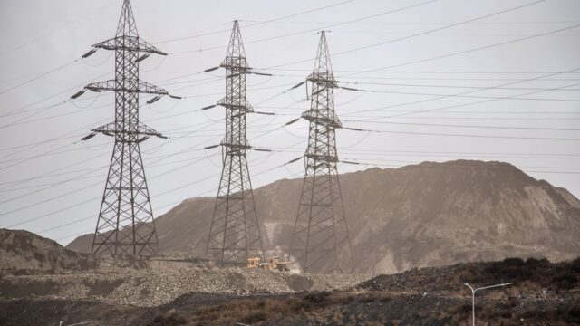 High voltage power lines and steel towers stretch across an industrial landscape in Zaporizhzhia, Ukraine.