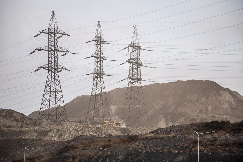 High voltage power lines and steel towers stretch across an industrial landscape in Zaporizhzhia, Ukraine.