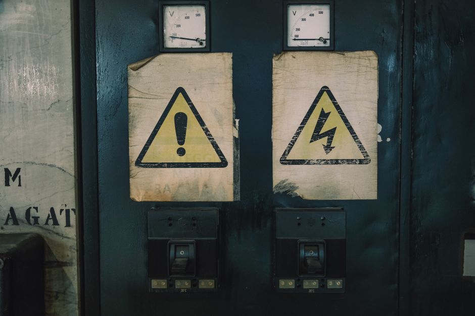 Close-up of industrial warning signs on an aged electrical panel.
