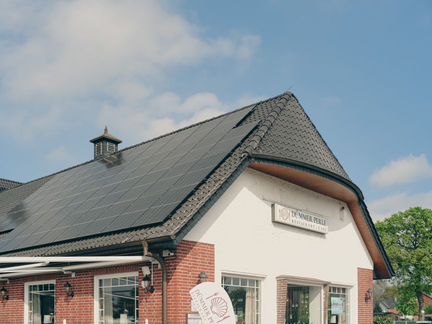 A red brick building with solar panels on the roof, under a clear blue sky, symbolizing sustainability and renewable energy.
