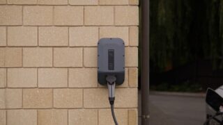 A wall-mounted electric vehicle charging station installed on a brick wall in Christchurch, New Zealand.