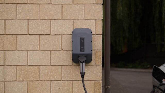 A wall-mounted electric vehicle charging station installed on a brick wall in Christchurch, New Zealand.