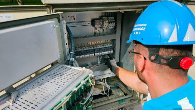 An electrician works on an outdoor fusebox, ensuring safety and functionality.