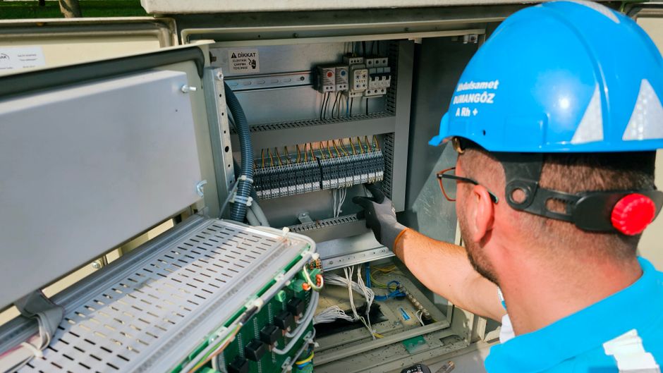 An electrician works on an outdoor fusebox, ensuring safety and functionality.