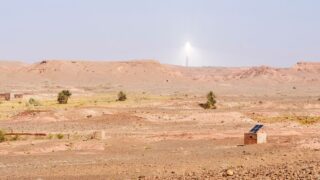 A scenic view of Atlas Mountains in Morocco featuring solar energy installations under a clear sky.