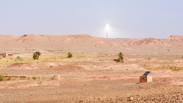 A scenic view of Atlas Mountains in Morocco featuring solar energy installations under a clear sky.