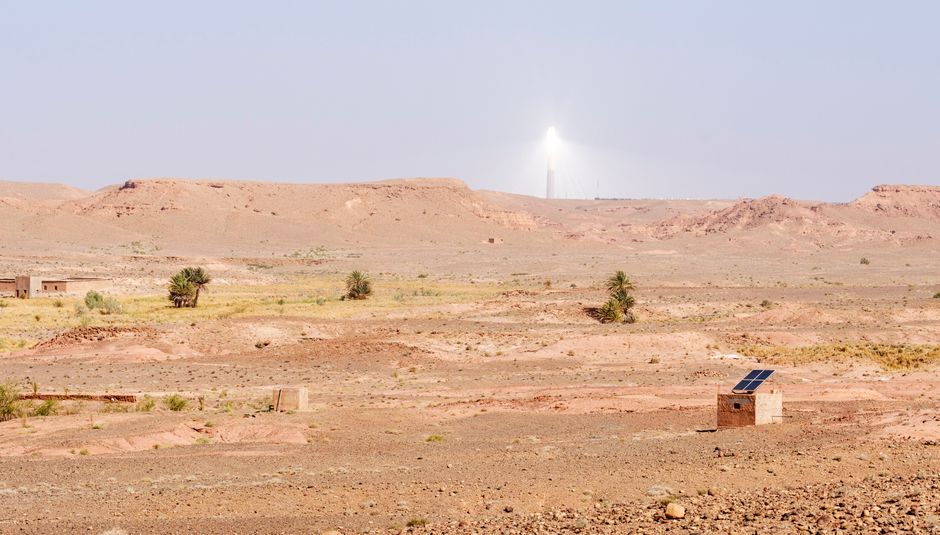 A scenic view of Atlas Mountains in Morocco featuring solar energy installations under a clear sky.