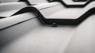 Detailed close-up of a black steel roof with prominent rivets and tiles.