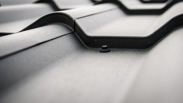 Detailed close-up of a black steel roof with prominent rivets and tiles.