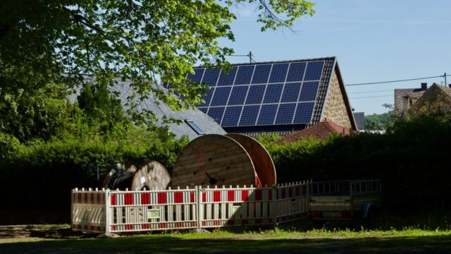 Barn with solar panels and cable reels in rustic countryside setting.