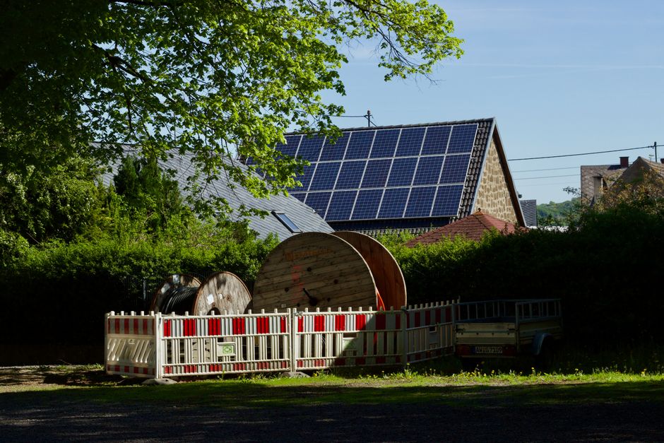 Barn with solar panels and cable reels in rustic countryside setting.