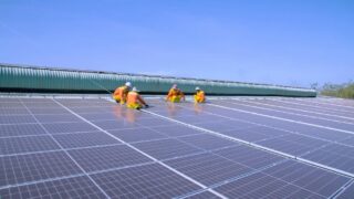 Workers installing solar panels on a sunny rooftop, emphasizing renewable energy and sustainability.