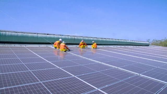 Workers installing solar panels on a sunny rooftop, emphasizing renewable energy and sustainability.