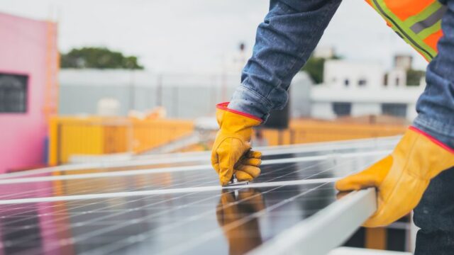 A solar technician performing maintenance on solar panels outdoors.