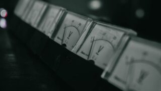 Close-up of vintage analog voltage meters in a dark industrial setting with a moody atmosphere.