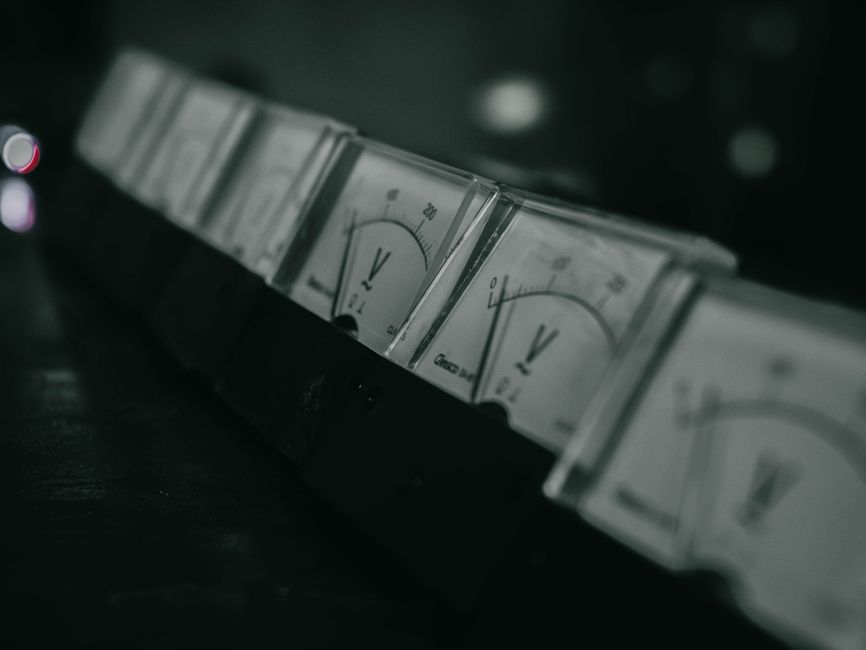 Close-up of vintage analog voltage meters in a dark industrial setting with a moody atmosphere.