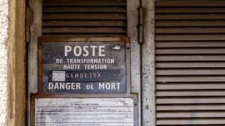 Rustic high voltage warning sign in Arles, Provence, symbolizing urban decay and industrial history.
