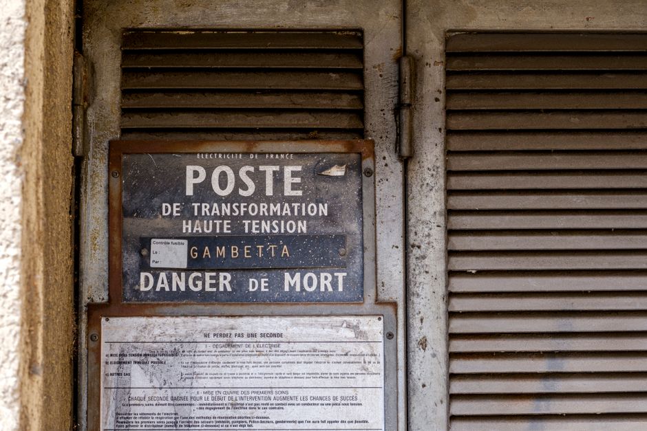 Rustic high voltage warning sign in Arles, Provence, symbolizing urban decay and industrial history.