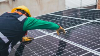 Technician installing solar panels on a rooftop for sustainable energy solutions.