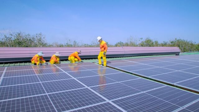 Workers install solar panels on a rooftop, promoting renewable energy and sustainability.