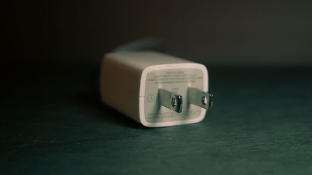 A focused view of a white wall charger plug lying on its side indoors.