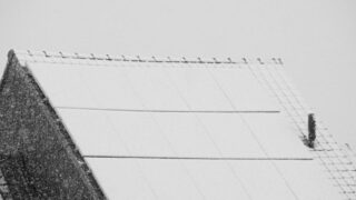 Snow-covered solar panels on a rooftop in winter, highlighting renewable energy challenges in cold climates.