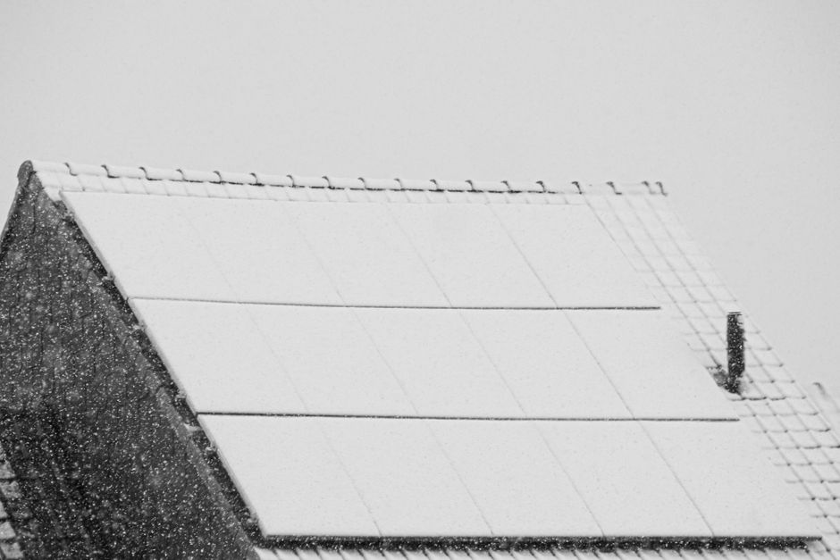 Snow-covered solar panels on a rooftop in winter, highlighting renewable energy challenges in cold climates.