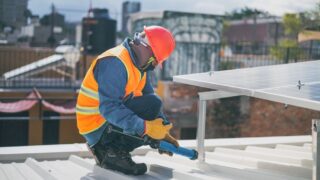 Technician in safety gear installing solar panels on a rooftop, ensuring energy efficiency.