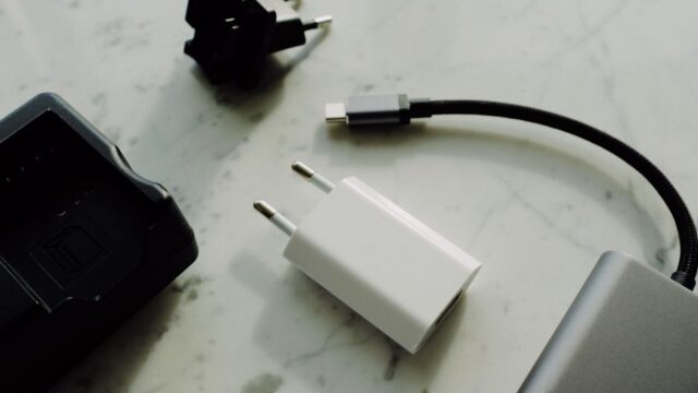 Set of various modern charging unit with adapter and small external battery pack with short cable placed on white marble table