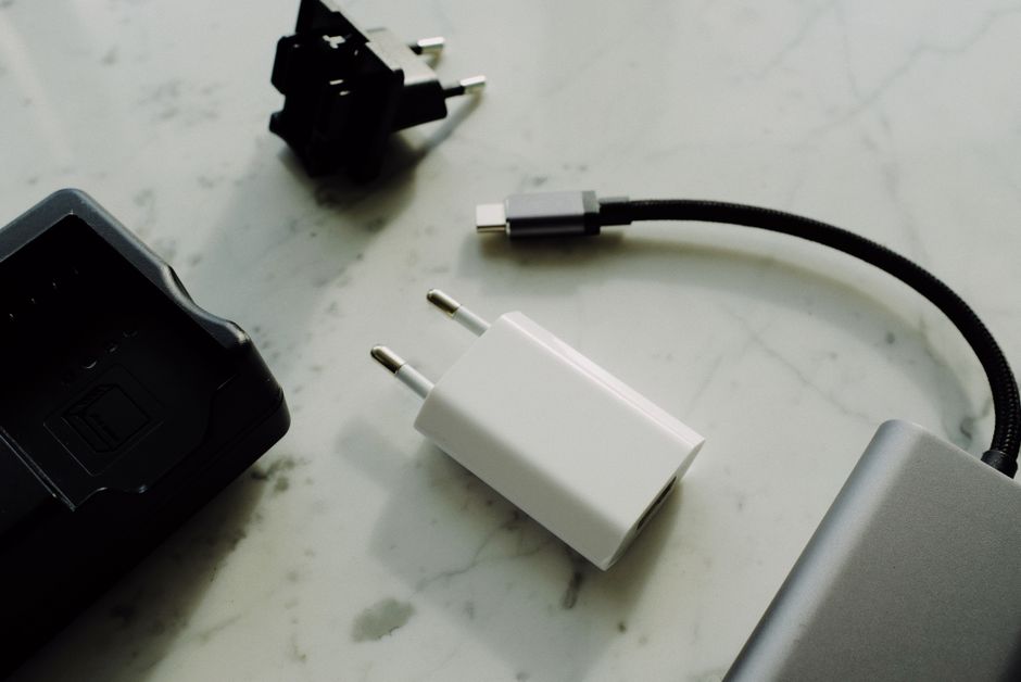Set of various modern charging unit with adapter and small external battery pack with short cable placed on white marble table