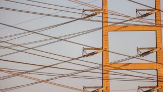High voltage power lines with sunset sky background, illustrating energy distribution.
