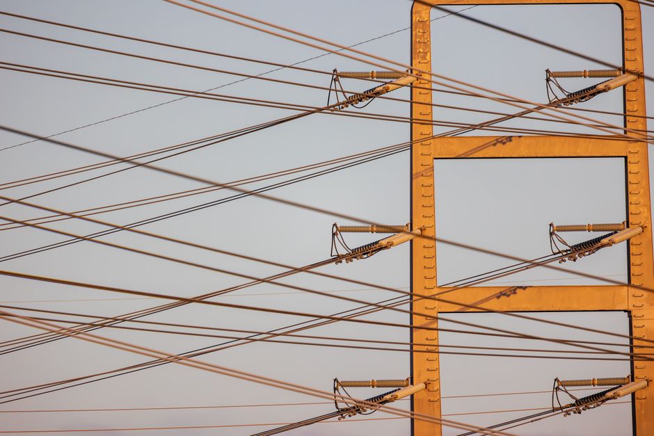 High voltage power lines with sunset sky background, illustrating energy distribution.