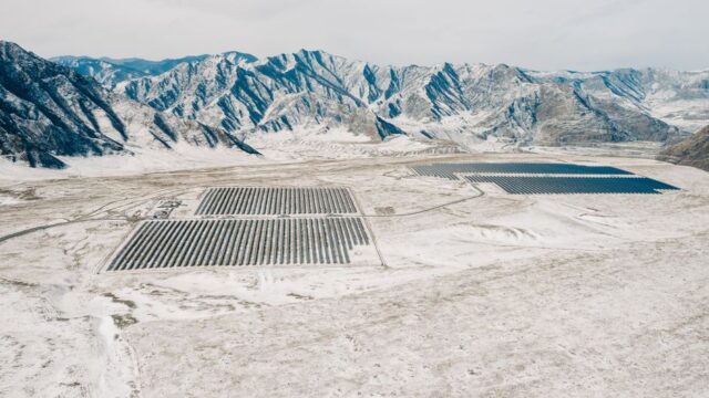 Drone shot of a solar farm amidst the snowy Altai Mountains, showcasing renewable energy in nature.
