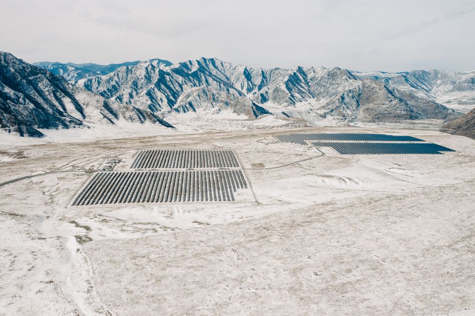 Drone shot of a solar farm amidst the snowy Altai Mountains, showcasing renewable energy in nature.