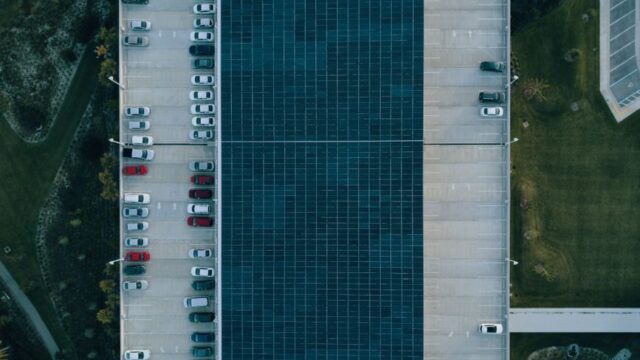 Top view of a parking lot with cars and solar panels, showcasing urban sustainability.