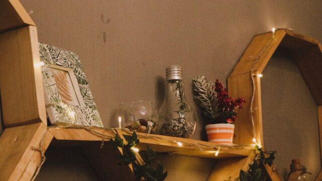 Warm and cozy wooden shelf decorated with plants, lights, and framed art, perfect for home decor inspiration.